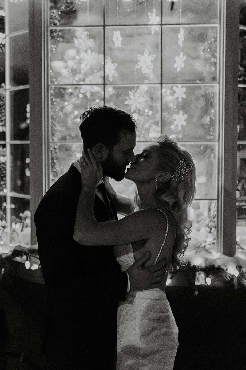 bride and groom kissing on black and white photo 