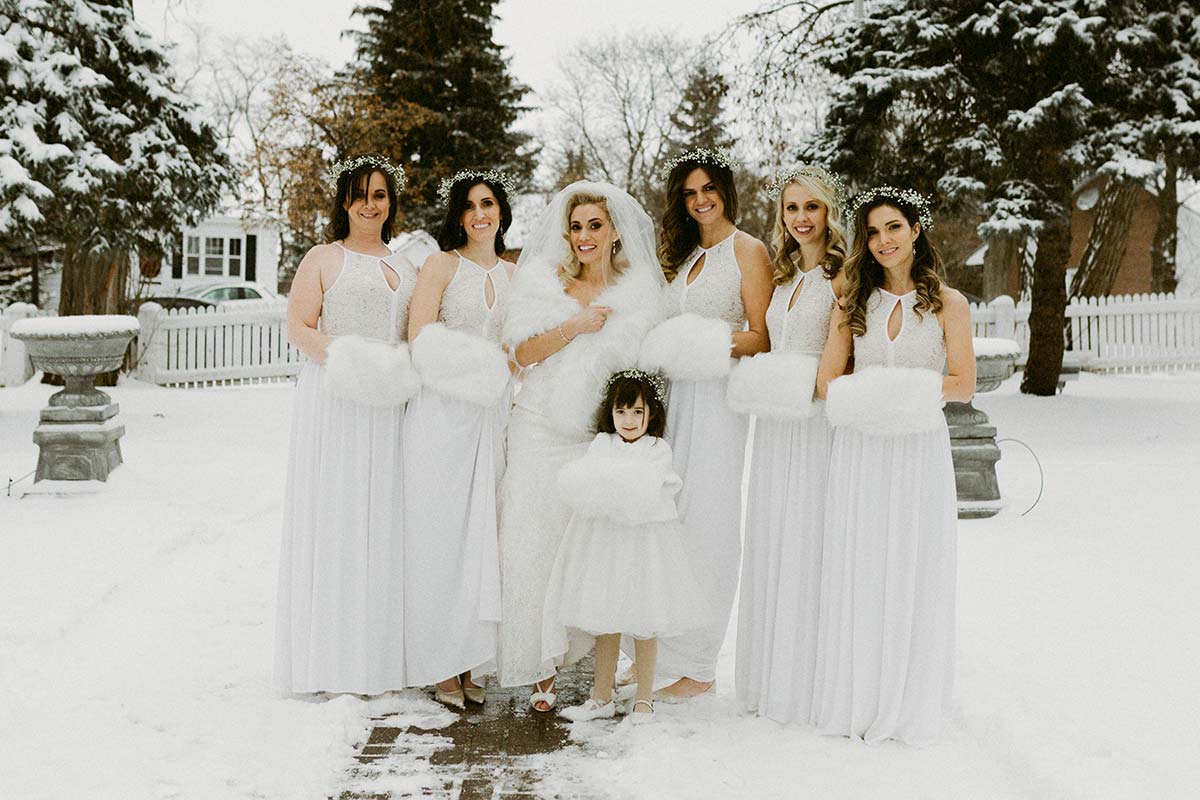 happy bride in feathers and bridesmaids outdoors at a winter wedding 