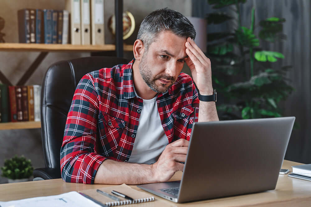 man looking stressed while looking at a computer