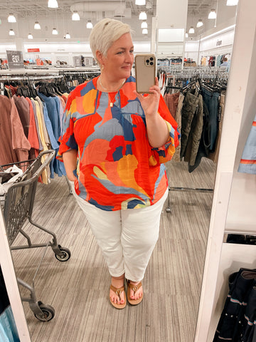 OneRealMomma modeling Universal standard white jeans, an anthropologie colorful blouse and madebymary gold jewelry while shopping on vacation
