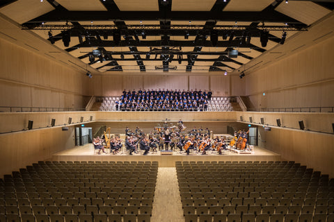 Picture of a concert hall with a live orchestra preparing to perform.