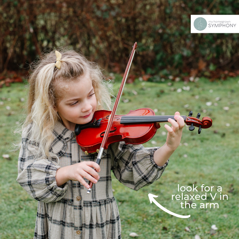 preschool aged girl holding a violin demonstrating how a child's arm should look when using a violin that is sized correctly