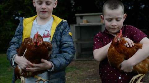 two boys holding chickens