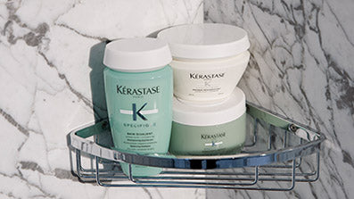 Kerastase Specifique Bain Divalent, Masque Rehydratant, Argile Equilibrante hair products in a shower corner basket