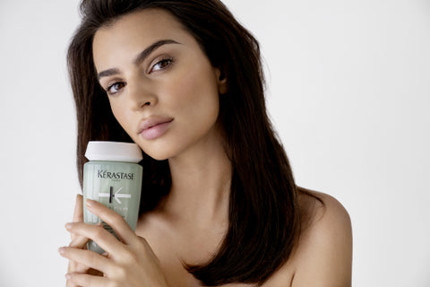 brunette model holds Kerastase Specifique Bain Divalent shampoo