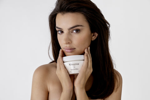 brunette model holding Kerastase Specifique Masque Rehydratant hair mask