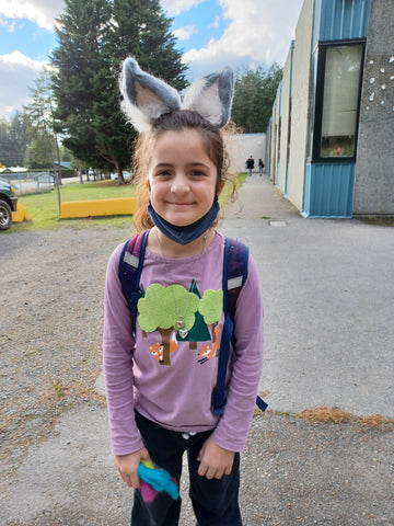 A young student wears grey and white felted lynx costume headband she made from wool