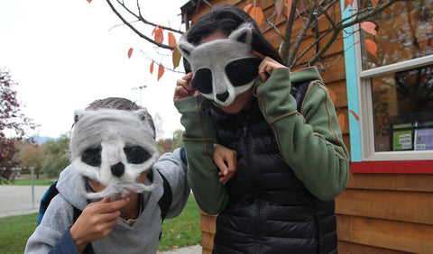 a parent and a child wear felted raccoon masks they needle felted our of wool