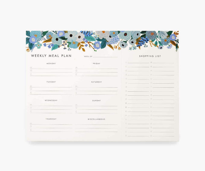 A meal planner notepad with blue flowers at the top. 