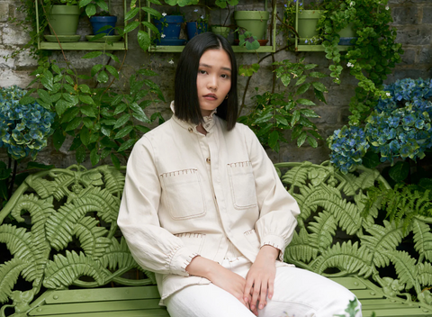 Woman sitting on a bench in a white denim jumpsuit