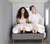 A couple looking distressed in a cramped room because the bed size was too big and did not fit the living arrangment