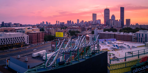 The Boston skyline looms behind the iconic John Hancock sign at Fenway Park