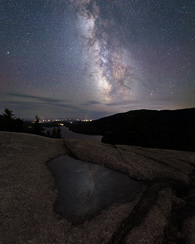 The Milky Way reflects in a puddle on top of North Bubble Rock in Acadia National Park, Maine