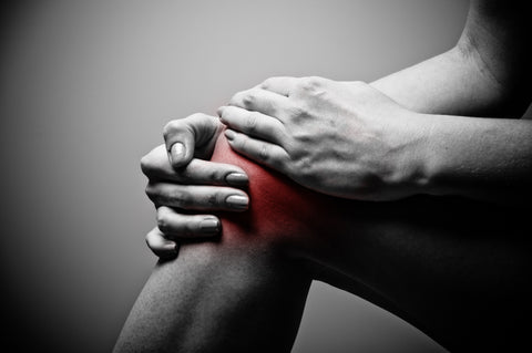 close up of a person holding their injured knee cap