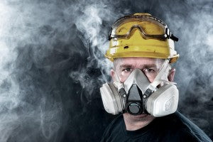 Man wearing respiratory protection equipment to protect himself from the smoke