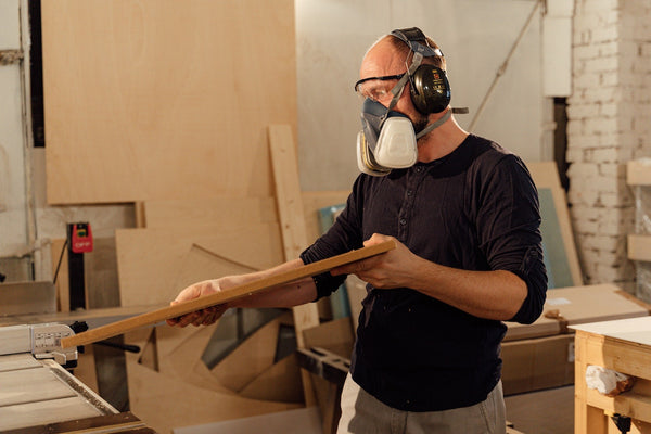 A man wearing an inappropriate half-face mask incorrectly that should be required as part of a proper respiratory protection programme but is clearly not while working in construction