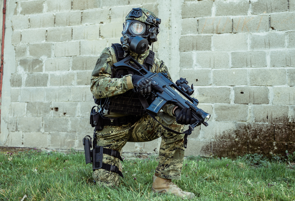 A crouching soldier wearing a perfectly fitted respirator mask and feeling confident because it has been face fit tested and will be effective in keeping him healthy and safe.