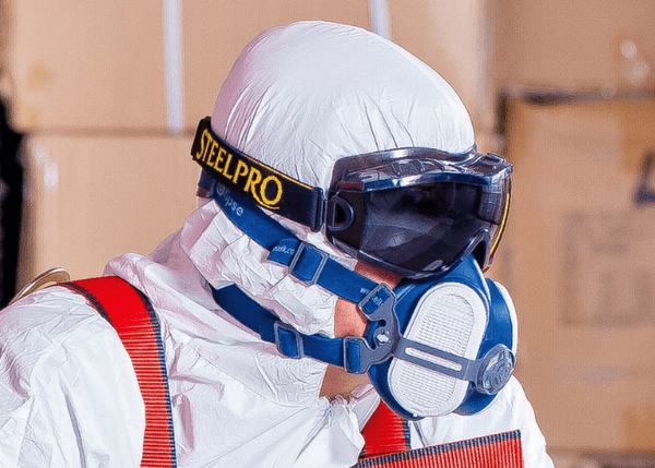 A worker wearing full PPE with a full-face mask ensuring their safety whilst working in hazardous environments.