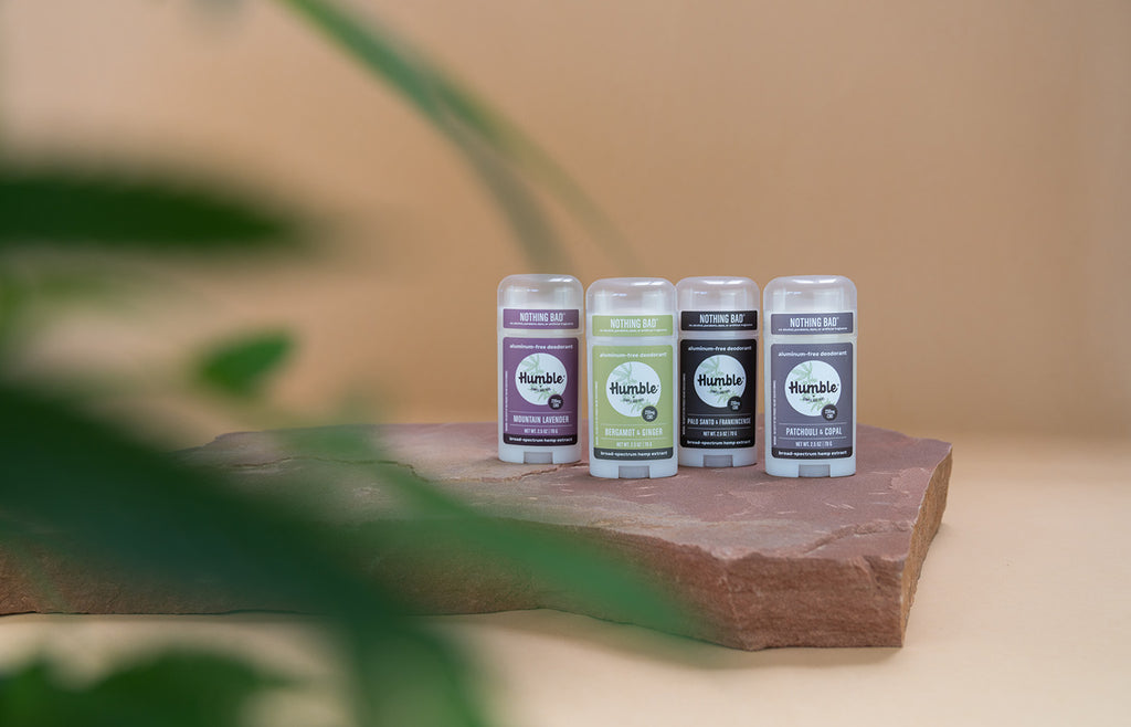 Four CBD deodorants lined up on a stone