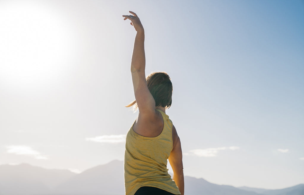 Woman with left arm raised looking into the distance