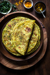 Thepla, a pile of Fenugreek (methi bhaji) rotli on plate, top thepla folded