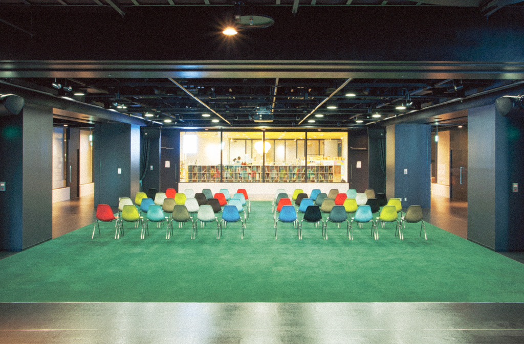 渋谷ヒカリエ8Fの会場。グリーンのカーペットにカラフルな椅子が置かれている