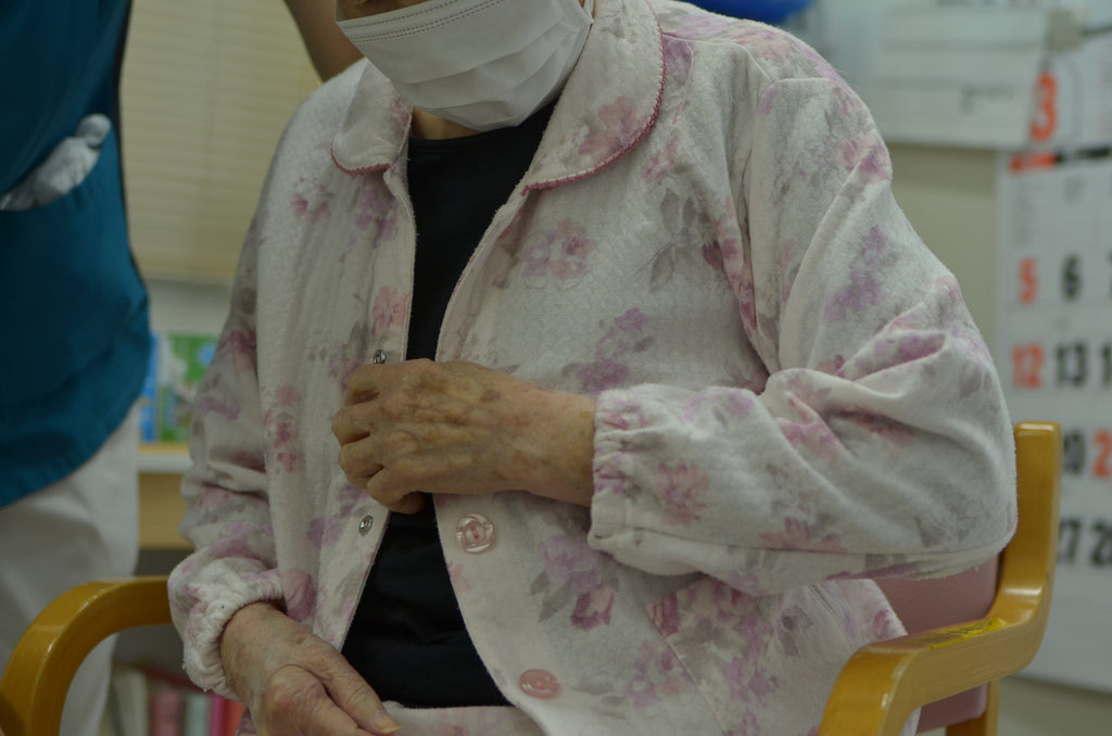 桜色の花の柄の柔らかい素材のジャケットを着ているおばあちゃん