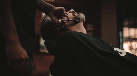 Man in barbers having beard trimmed