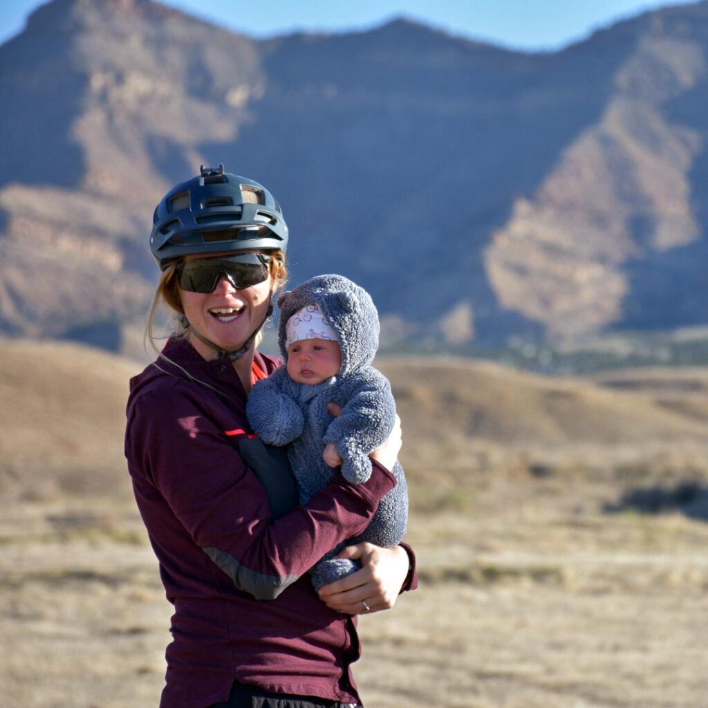 Cooper Ott holding her baby with mountains in the background. 