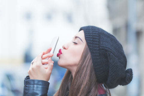 A woman holding a refurbished phone in her hands pouting her lips