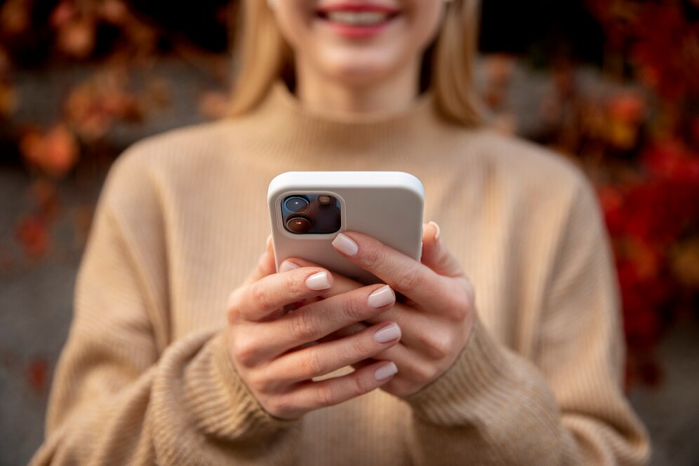 Image shows women smiling at her phone.