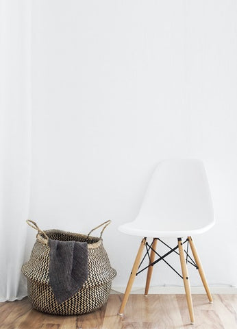 White chair and storage basket sat on laminate floor against white wall