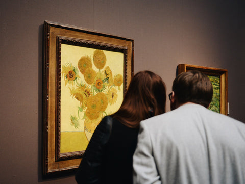 Man and woman at art museum admiring Sunflowers painting by Van Gogh 