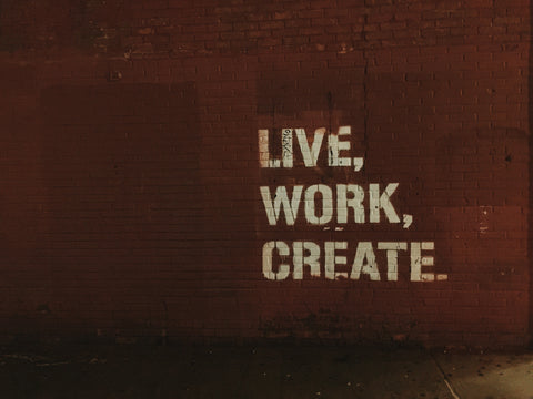 Creative quote "live, work, create" graffitied on red wall