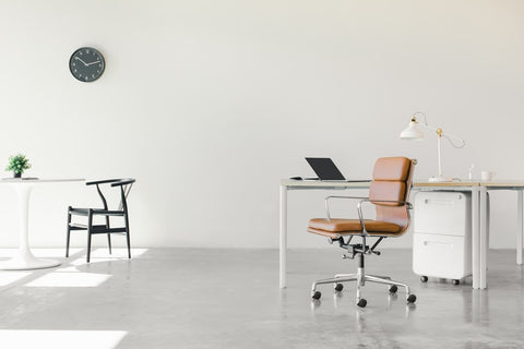 Dynamic office furniture including white desk and pale, brown leather chair