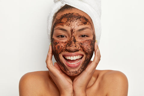 Close up shot of attractive woman keeps hands under chin, exfoliates skin with coffee scrub