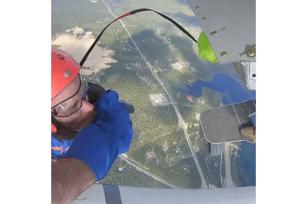 skydivebc skydiver hanging from plane