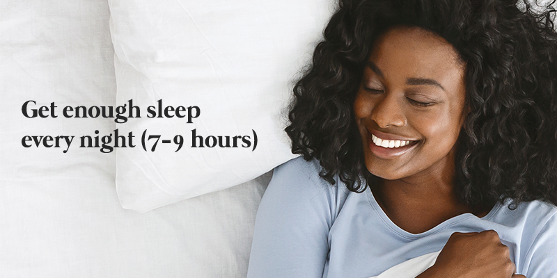 black woman lying at the bed closed eyes while she smile