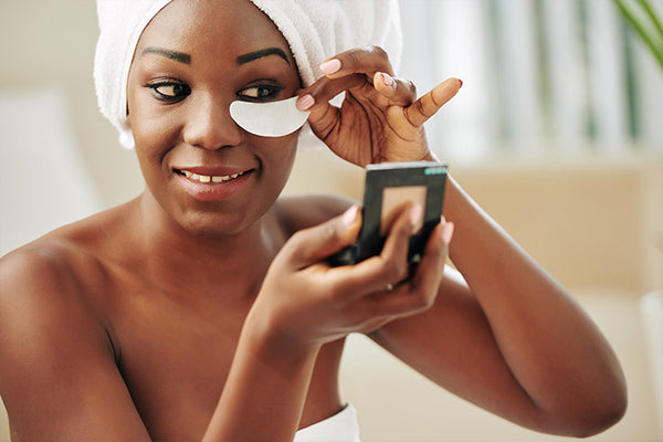 woman wearing towel on her body and hair looking at the make up miror 
