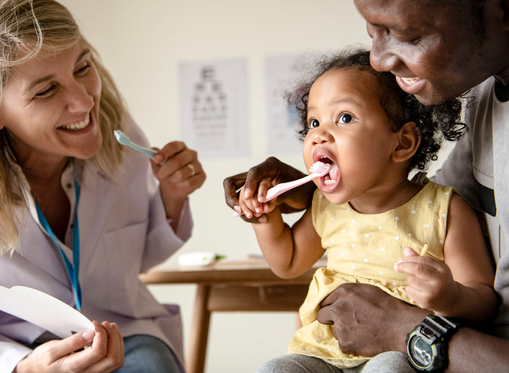 Dentiste montrant à une petite fille comment se brosser les dents