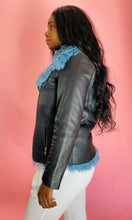 Load image into Gallery viewer, Side view of a size L VEDA black leather jacket with baby blue shearling fur on the inside styled over a black top and white pants on a size 10/12 model.
