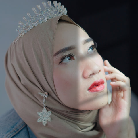 Image of a light skinned woman with a headscarf and a brooch pinning it together