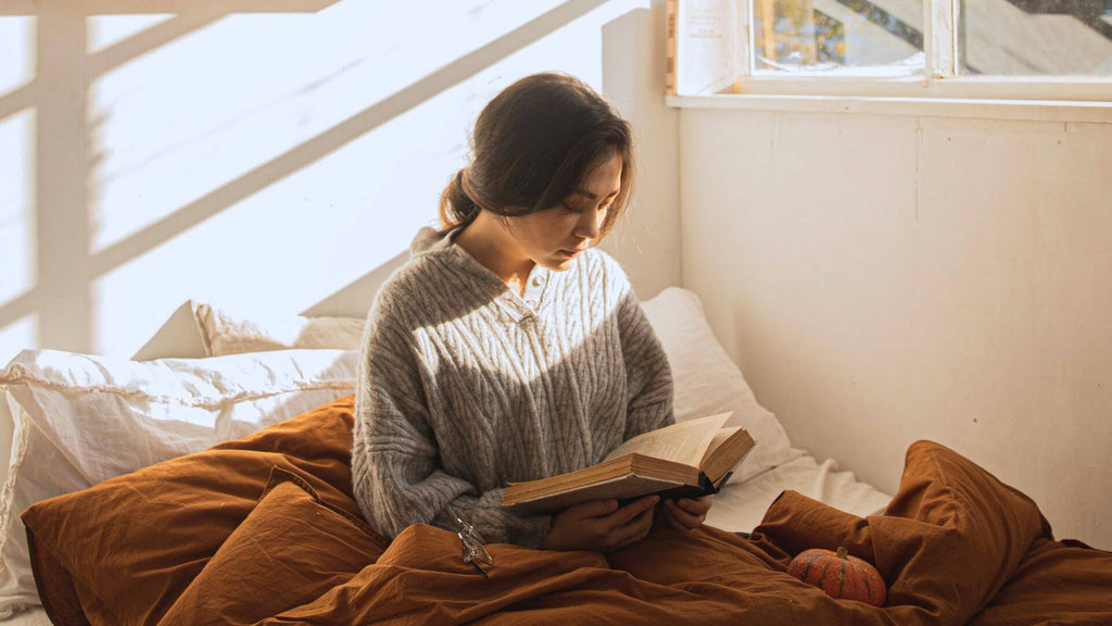 Woman escaping into a book in her bed