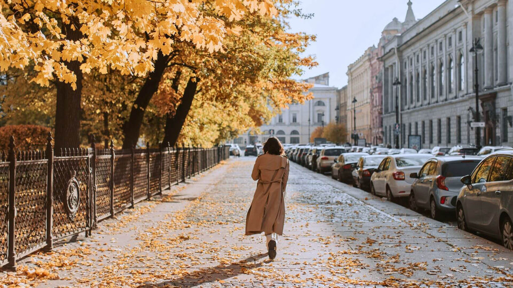 Woman in a jacket walking down a tree lined street