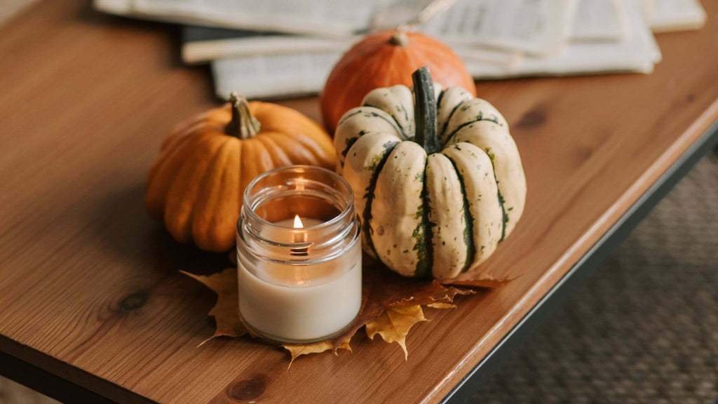 An arrangement of leaves, small pumpkins, and candles on a coffee table