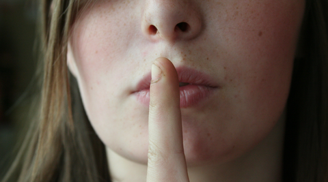 woman with finger in front of lips to make ssshhh noise hush