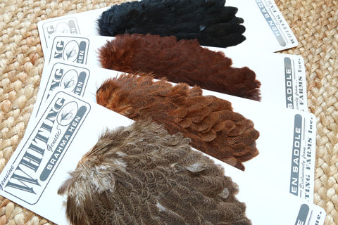 A Picture of several Whiting Farms Brahma Hen Saddles (Including: Black and Mottled Gray)