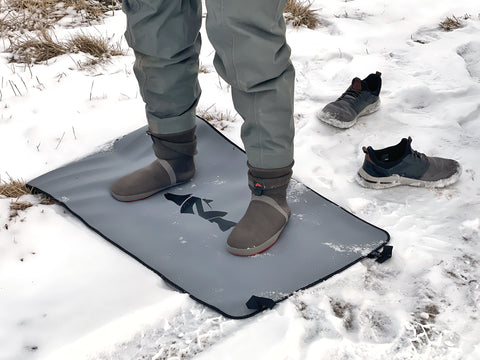 Neoprene Wader Changing Mat from NIRVANA On The Fly unrolled and in use as someone stands on it in Waders.