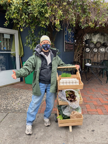 woman with wooden farmers market cart and produce in temescal, oakland