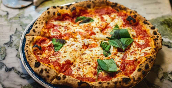 Freshly cooked Margherita pizza on a plate with basil on top